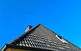 ventana de techo abierta en estilo velux con tejas negras. foto