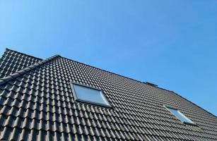 ventana de techo abierta en estilo velux con tejas negras. foto