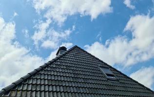 ventana de techo abierta en estilo velux con tejas negras circundantes foto