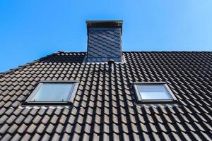 Roof window in velux style with black roof tiles. photo