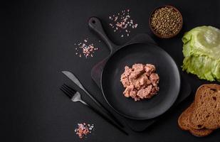 Delicious canned tuna meat on a black ceramic plate on a dark concrete background photo