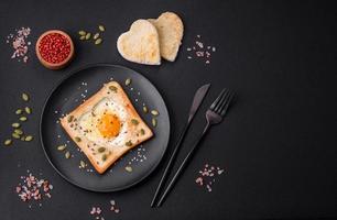 huevo frito en forma de corazón en pan tostado con semillas de sésamo, semillas de lino y semillas de calabaza en un plato negro foto