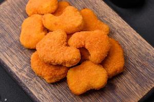 Delicious fresh crispy chicken nuggets on a dark concrete background photo