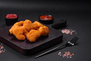 Delicious fresh crispy chicken nuggets on a dark concrete background photo