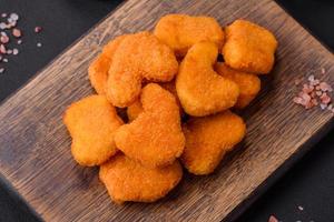 Delicious fresh crispy chicken nuggets on a dark concrete background photo