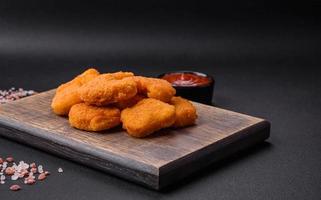 Delicious fresh crispy chicken nuggets on a dark concrete background photo