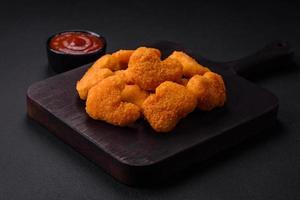 Delicious fresh crispy chicken nuggets on a dark concrete background photo