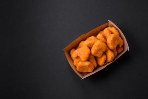 Delicious fresh crispy chicken nuggets on a dark concrete background photo