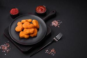 Delicious fresh crispy chicken nuggets on a dark concrete background photo