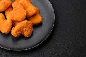 Delicious fresh crispy chicken nuggets on a dark concrete background photo