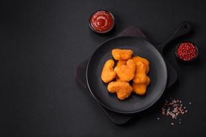 Delicious fresh crispy chicken nuggets on a dark concrete background photo