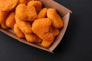 Delicious fresh crispy chicken nuggets on a dark concrete background photo