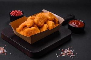 Delicious fresh crispy chicken nuggets on a dark concrete background photo