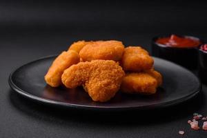 Delicious fresh crispy chicken nuggets on a dark concrete background photo