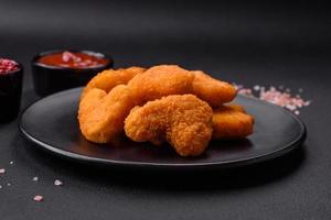 Delicious fresh crispy chicken nuggets on a dark concrete background photo