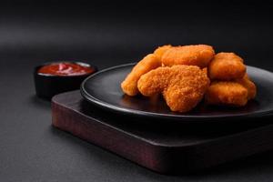 Delicious fresh crispy chicken nuggets on a dark concrete background photo