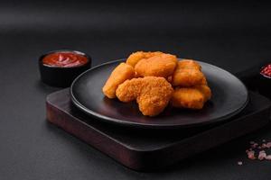 Delicious fresh crispy chicken nuggets on a dark concrete background photo