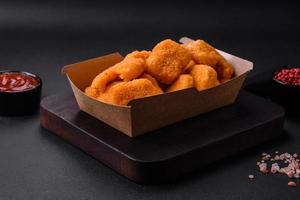 Delicious fresh crispy chicken nuggets on a dark concrete background photo