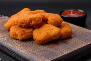 Delicious fresh crispy chicken nuggets on a dark concrete background photo