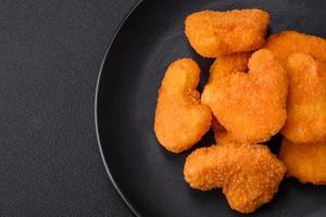 Delicious fresh crispy chicken nuggets on a dark concrete background photo