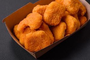 Delicious fresh crispy chicken nuggets on a dark concrete background photo