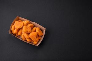 Delicious fresh crispy chicken nuggets on a dark concrete background photo