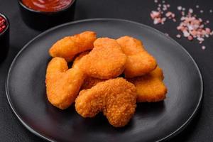 Delicious fresh crispy chicken nuggets on a dark concrete background photo