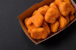 Delicious fresh crispy chicken nuggets on a dark concrete background photo