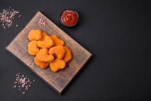 Delicious fresh crispy chicken nuggets on a dark concrete background photo