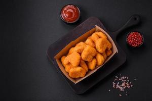 Delicious fresh crispy chicken nuggets on a dark concrete background photo