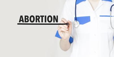 Doctor writing text abortion with marker, medical concept photo