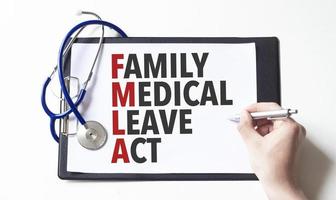 Doctor holding a pen and card with text family medical leave act, medical concept photo