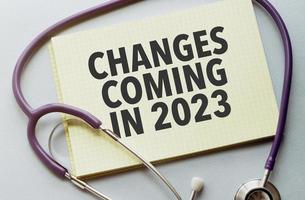On a purple background a stethoscope with yellow list with text changes coming in 2023 photo