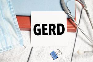 White notepad with the words gerd and a stethoscope on wooden background photo