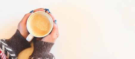 top view coffee caramel woman coffee with hand holding a cup on the wood table, caramel coffee cup in the morning - hot caramel macchiato photo