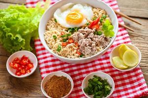 noodles bowl with boiled egg minced pork vegetable spring onion lemon lime lettuce celery and chili on table food , instant noodles cooking tasty eating with bowl - noodle soup photo