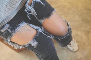 torn pants , torn jeans, close up girl wear jean - women knees in jeans holes in jeans, fashion clothing. Hips and knees in fashionable jeans photo