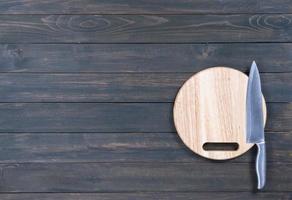 Kitchen knife on wooden round cutting board close up photo