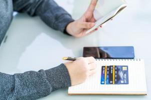 Woman writing on notebook with credit card and smartphone  desk photo