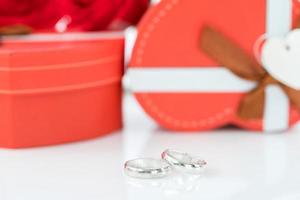 anillo de bodas y caja en forma de corazón en blanco foto