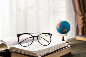 Reading glasses put on open book beside the window photo