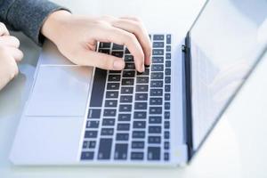 Woman working at home office using laptop searching web, browsing information photo