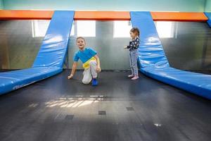 hermano con hermana jugando en el patio interior del centro de juegos, saltando en trampolín. foto