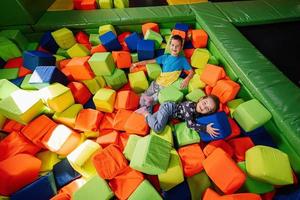 Brother with sister playing at indoor play center playground in color cubes pool. photo