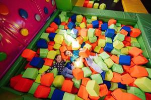 Brother with sister playing at indoor play center playground in color cubes pool. photo