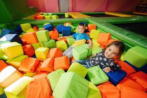 Brother with sister playing at indoor play center playground in color cubes pool. photo