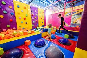 Brother with sister playing at indoor play center playground. photo