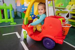 Kids playing at indoor play center playground , girl in toy car. photo