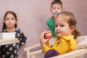 Three kids eat delicious tasty sweet color macarons. photo