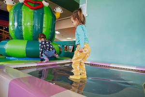 Happy sisters playing at indoor play center playground in water trampoline. photo